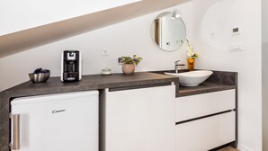A modern kitchen with a built-in refrigerator, a coffee machine, a sink, and a potted plant. - Lucio suites - Apartment 3 with balcony (Split)