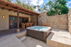Un espace bien-être comprenant un jacuzzi, des meubles en bois et des murs en pierre.