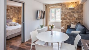 A cozy room with a stone wall, a bed, a dining table with chairs, and a sofa.