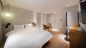 Une chambre d’hôtel avec un grand lit, un bureau, une chaise et une lampe de bureau.