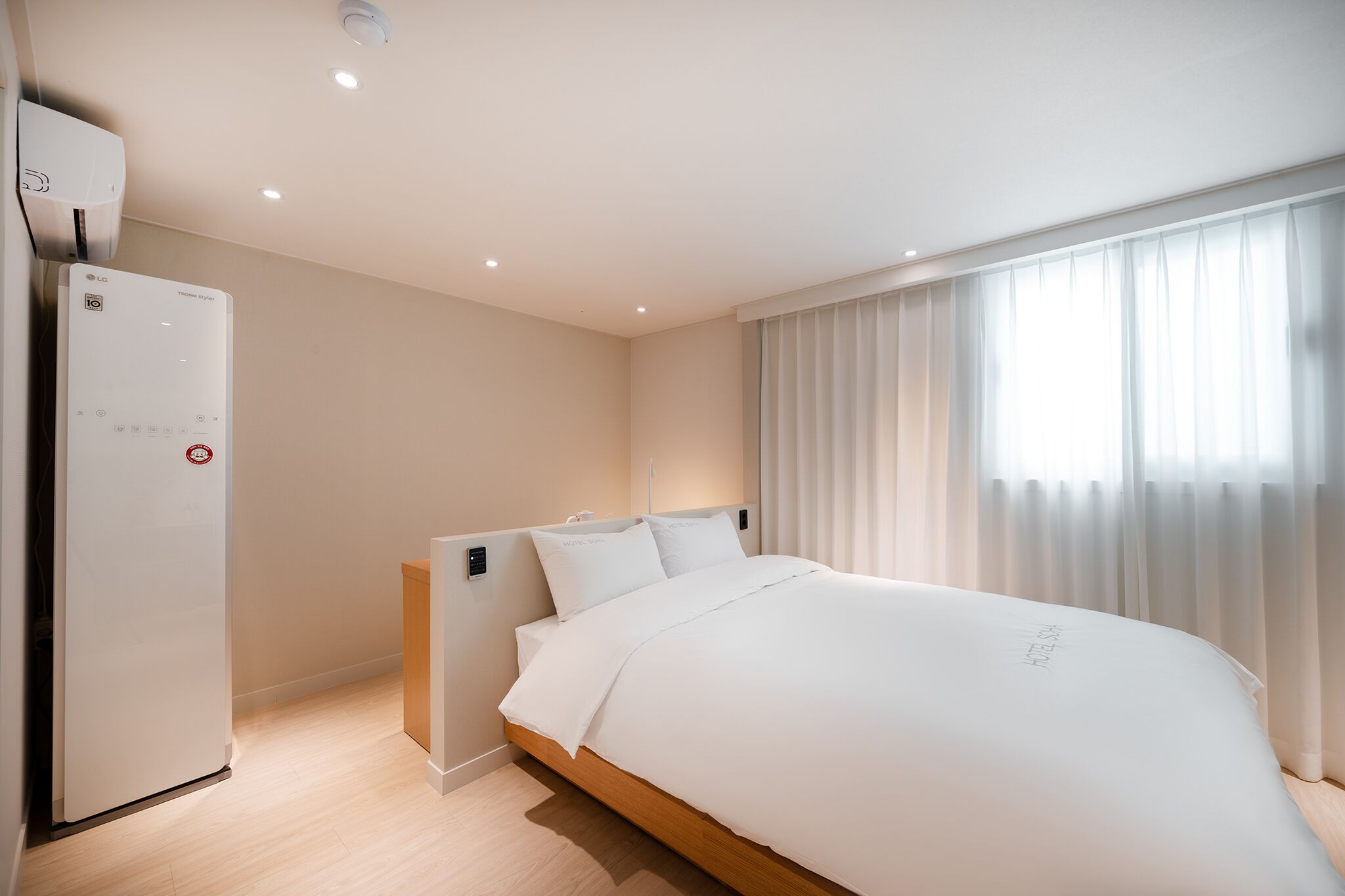 Una camera d'albergo moderna con un letto grande, un riscaldatore integrato e una finestra con tende leggere.