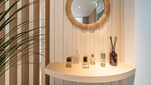 Un meuble-lavabo de salle de bain avec un miroir, une plante et plusieurs flacons de produits de toilette.