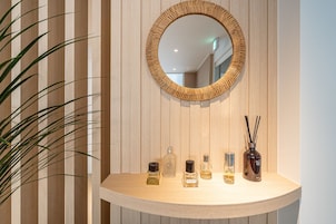A bathroom vanity with a mirror, a plant, and several bottles of toiletries.