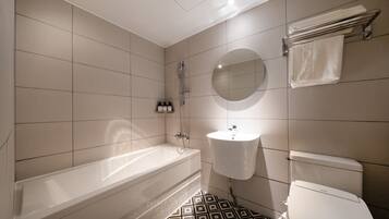 Un baño moderno con bañera, lavamanos e inodoro, que destaca por un suelo con estampado geométrico.