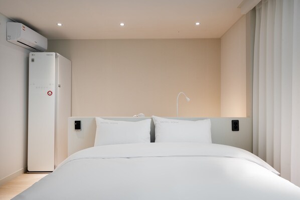 Una habitación de hotel moderna con una cama, aire acondicionado de pared y panel de control.