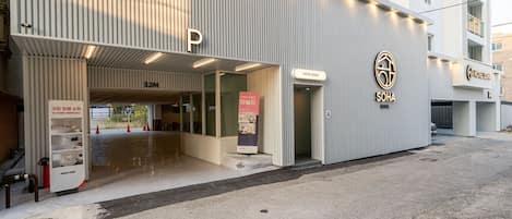 A hotel entrance with a modern design, a parking sign, and a visible room number.