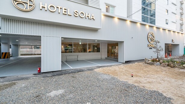 Une entrée d’hôtel moderne, avec une enseigne bien visible portant l’inscription « HÔTEL SOHA ».