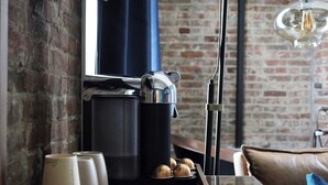 Una cocina con cafetera, una bandeja con tazas de café y una pared de ladrillo.