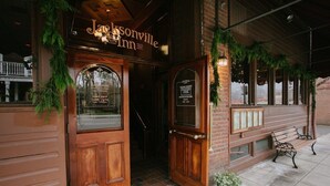 A wooden entrance with a sign for Jacksonville Inn, a bench outside, and a brick wall.