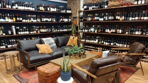 Une cave à vin avec des étagères remplies de bouteilles, un canapé en cuir, une table basse et un tapis à motifs.