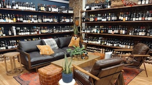 Una bodega con estantes llenos de botellas de vino, un sofá de cuero, una mesa de centro y una alfombra estampada.