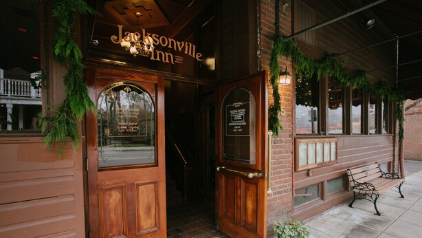 A brick building with a wooden door and a sign that reads "Jacksonville Inn 1967". - Experience historic Jacksonville! This 1 BR Queen Guest Room offers boutique charm in the heart of wine country. Walk to the Britt Festival, Nespresso machine included. Ideal for a downtown escape for two. (Jacksonville)