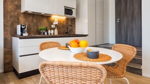A modern kitchen with white cabinetry, a microwave, and a bowl of oranges on the counter. - Lucio Suites- Apartment 2 (Split)