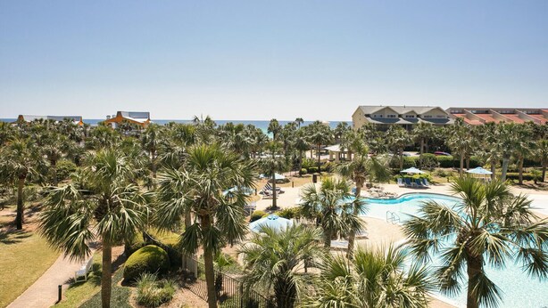 A resort with a swimming pool, palm trees, and beachfront views.
