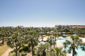 Un complexe hôtelier doté d’une piscine, de palmiers et offrant une vue sur la plage.