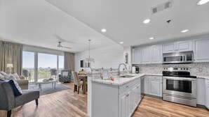 A modern kitchen with a central island, stainless steel appliances, and a dining area with a view.