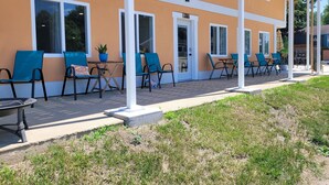 A building with a row of outdoor seating areas, each with a chair and a small table.
