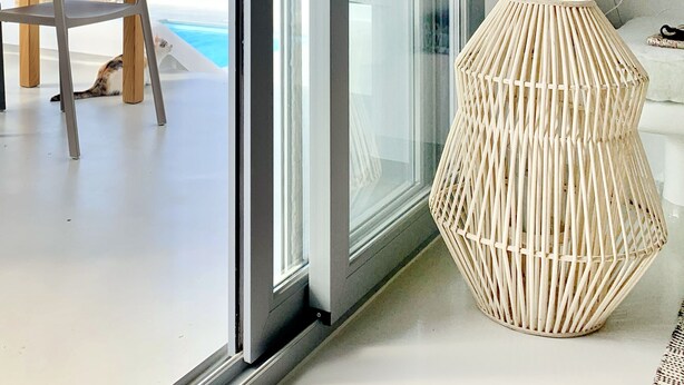 Ein modernes Zimmer mit einer Schiebeglasdoor zum Balkon mit Pool und Meerblick.