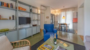 A modern living room with a blue armchair, a flat-screen TV, and a bookshelf. - BnButler - Brivio 21 (Milan)