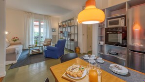 A modern kitchen with a dining area, a blue chair, and a breakfast tray. - BnButler - Brivio 21 (Milan)