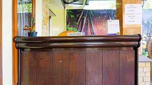 A reception desk with a wooden panel design, a sign labeled "RECEPTIONIS," and a calendar on the wall.