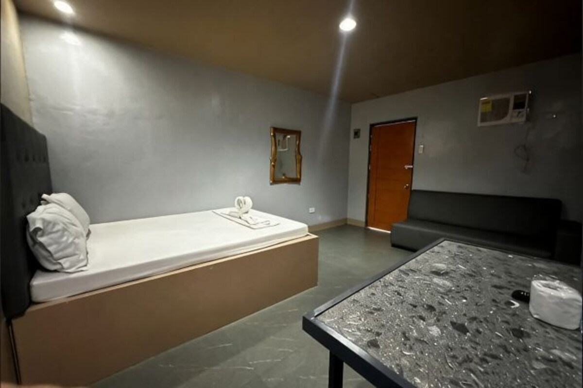 A room with a bed, a table, a bench, and a door.