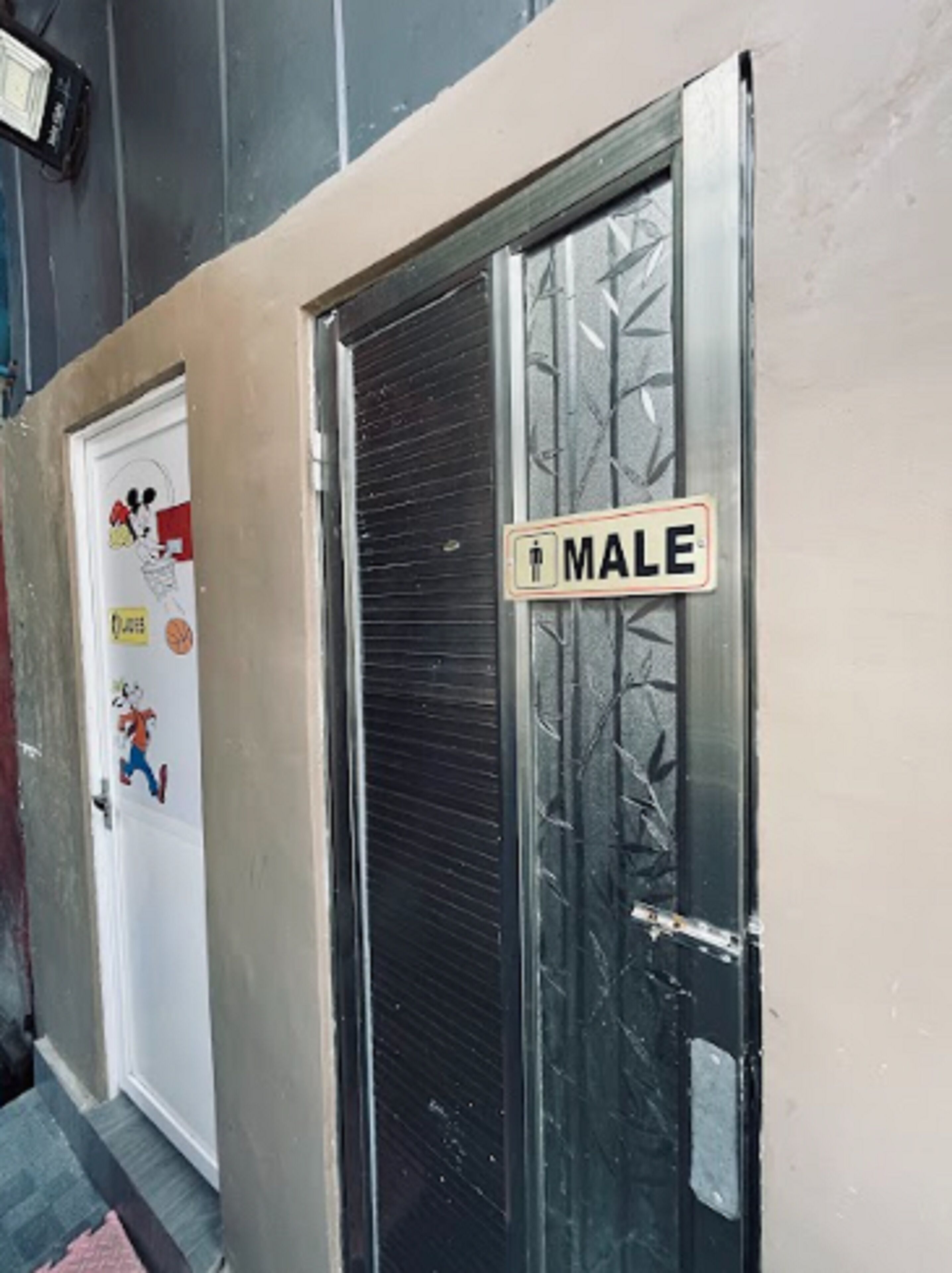 Eine Tür mit einem Schild 'MALE' und eine Tür mit Aufklebern.