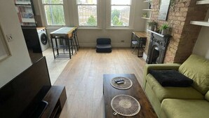 Un salón amplio con sofá, mesa de centro y chimenea. Grandes ventanas ofrecen luz natural y vistas a la ciudad.