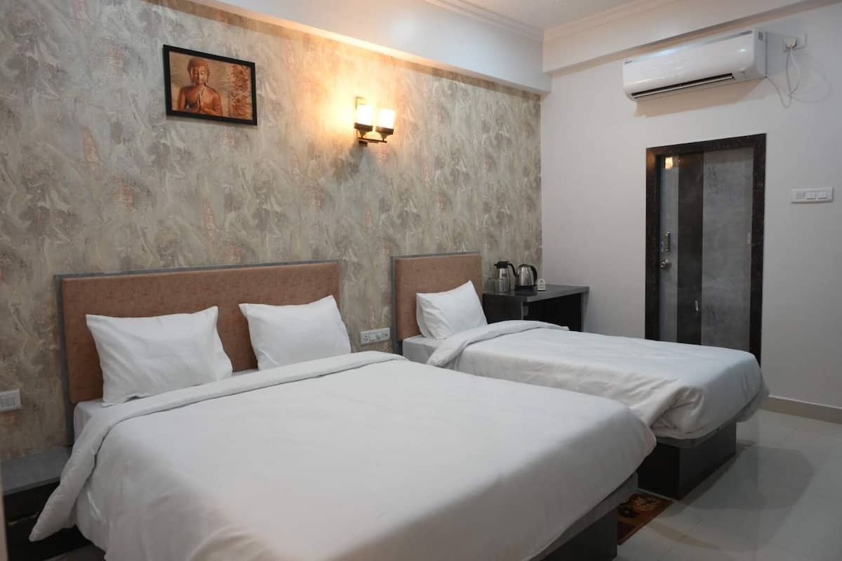 Habitación de hotel con dos camas, pared con diseño de mármol, una obra de arte enmarcada, una mesita de noche con hervidor y un equipo de aire acondicionado.