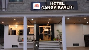Der Eingang des Hotel Ganga Kaveri mit einer modernen Fassade, einem Schild und einer Treppe zum Eingang.