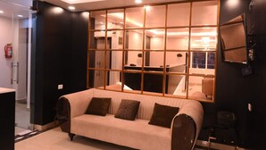 Ein modernes Zimmer mit großem Fenster, einer Couch, einem Schreibtisch und einem Sessel.