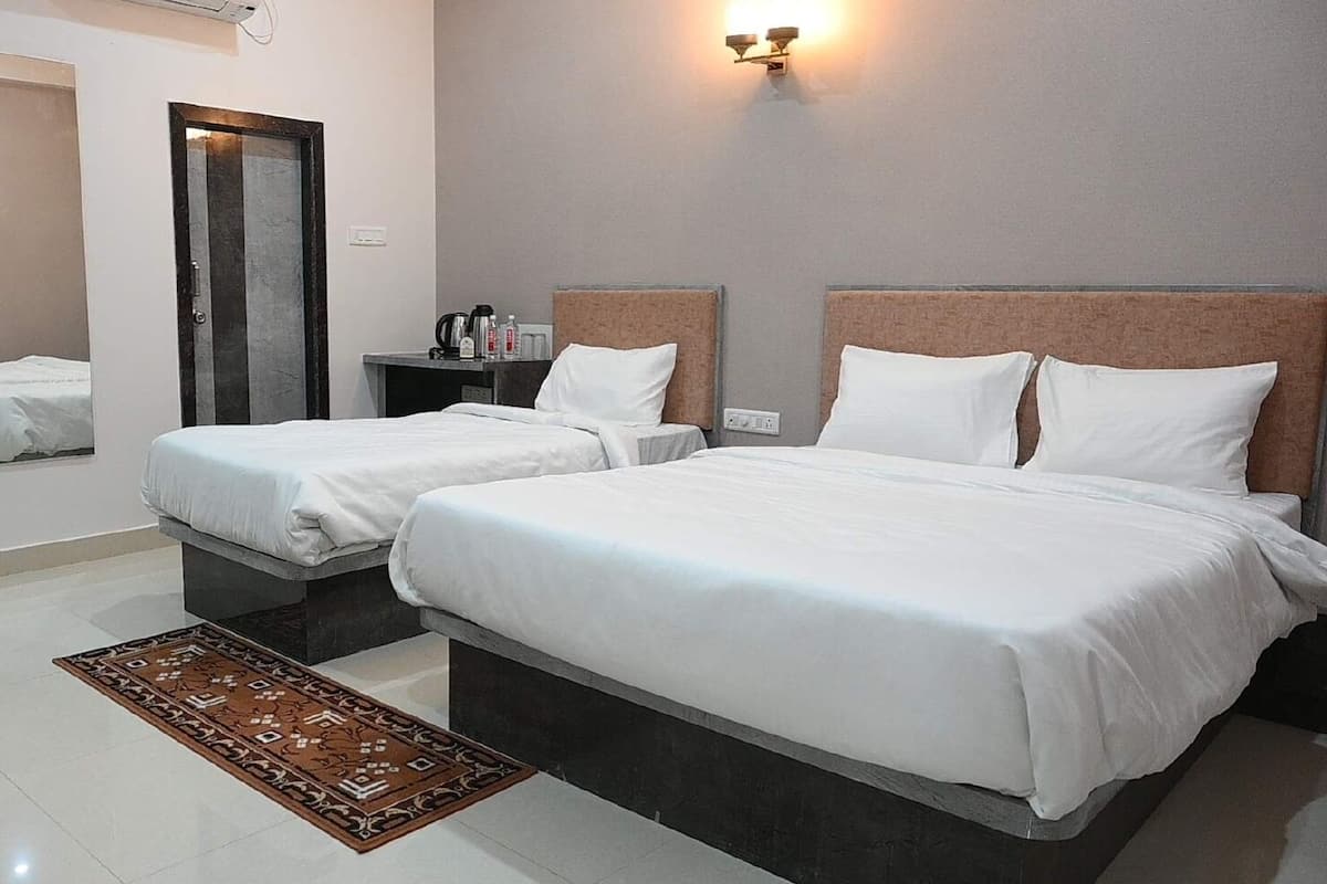 Habitación de hotel con dos camas, una mesita, un espejo y una lámpara fijada a la pared.