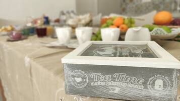 A table set with various items including a framed box labeled "Tea Time," cups, and a bowl of fruit.