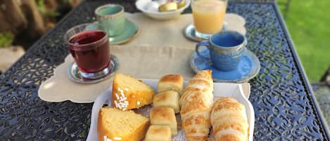 Una mesa con un plato de pasteles, un vaso de jugo y una taza de té.