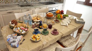 Une table de petit-déjeuner dressée avec divers aliments, notamment du pain, des fruits et des boissons.