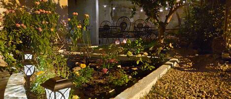 A garden with a pathway, lanterns, and flowering plants.