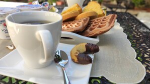 Une tasse de café blanc, une assiette de biscuits et une cuillère sur une table recouverte d’une nappe en dentelle.