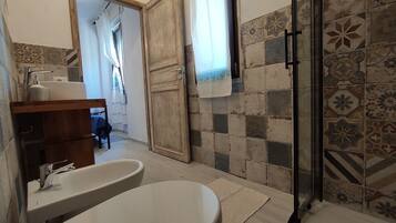 Un baño con lavamanos, inodoro y zona de ducha.