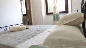 Une chambre à coucher avec un lit, une fenêtre avec des rideaux, une porte et un téléviseur fixé au mur.