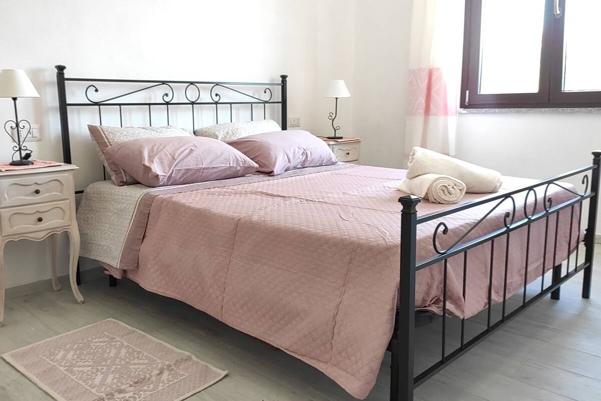 Une chambre à coucher bien rangée, avec un lit, des tables de chevet, des lampes et un tapis.