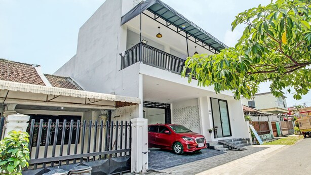 A two-story building with a red car parked in front. - Hotel O Sirih Gading Family Guest House (Tulungagung)