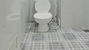 A bathroom with a toilet, shower, and patterned floor tiles. - Hotel O Sirih Gading Family Guest House (Tulungagung)
