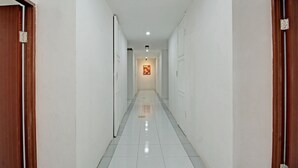 A corridor with white walls and a tiled floor, leading to a door at the end. - Hotel O Sirih Gading Family Guest House (Tulungagung)