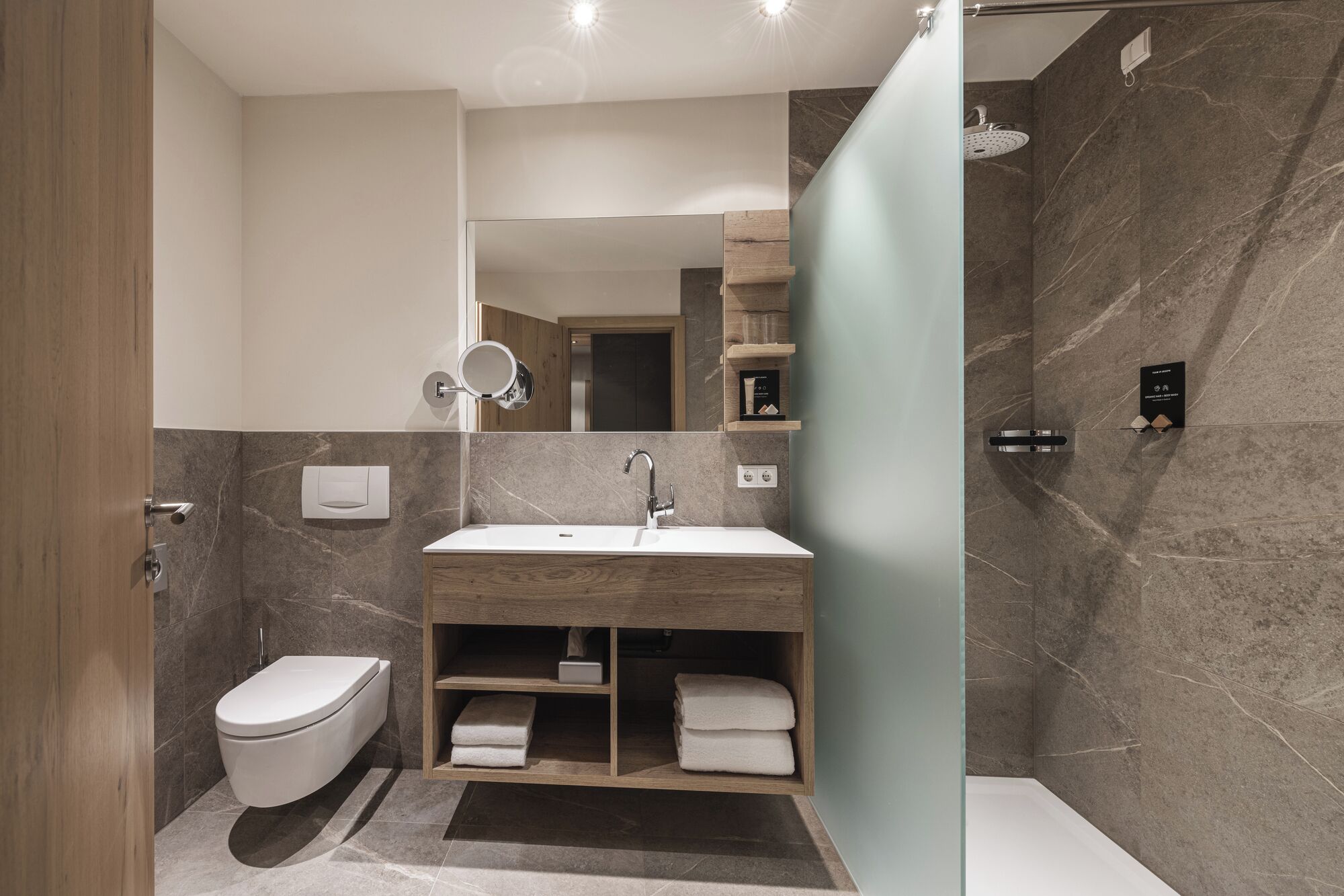A modern bathroom with a toilet, sink, and shower.