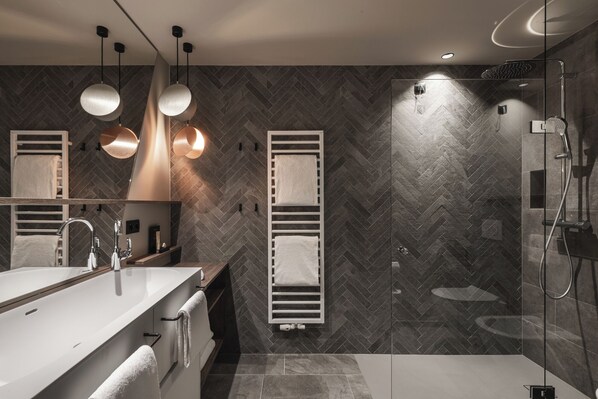 A modern bathroom with a large mirror, a white sink, and a glass shower enclosure. - Falkensteiner Family Resort Lido (Chienes)