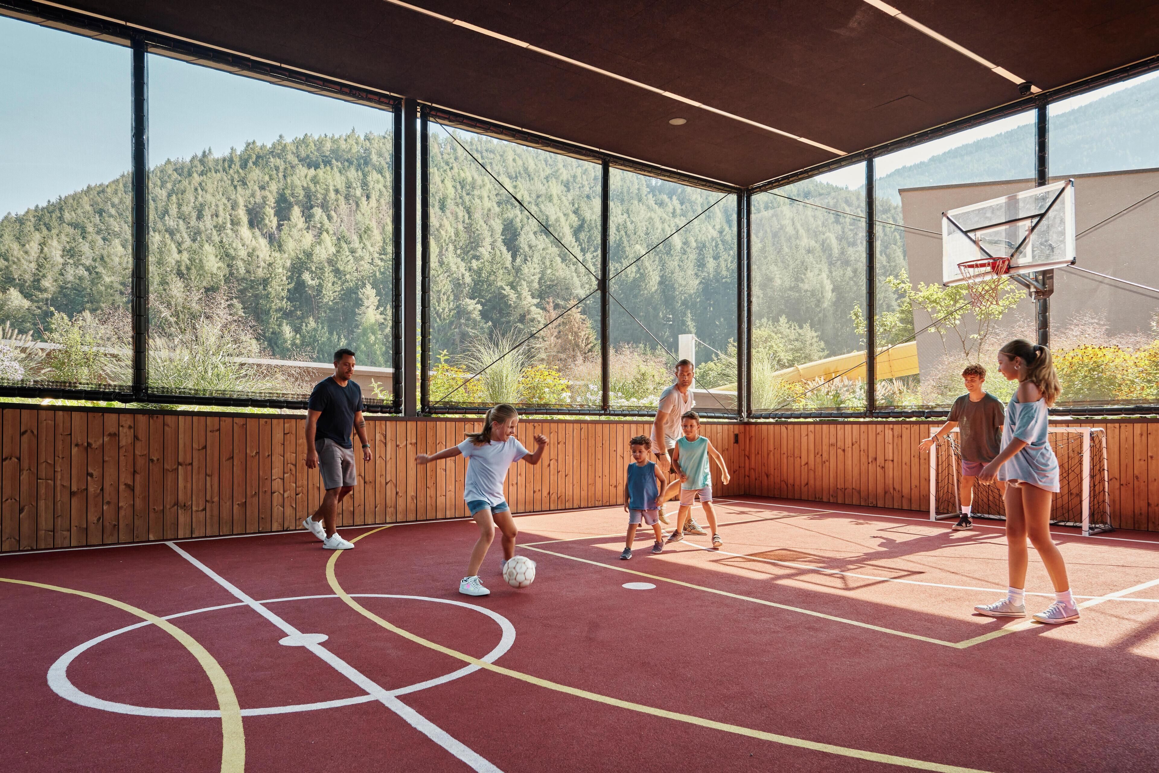 An indoor basketball court with a wooden floor and a basketball hoop.