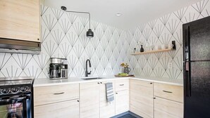 Une cuisine moderne avec un four noir, des armoires blanches et un revêtement mural à motifs géométriques.