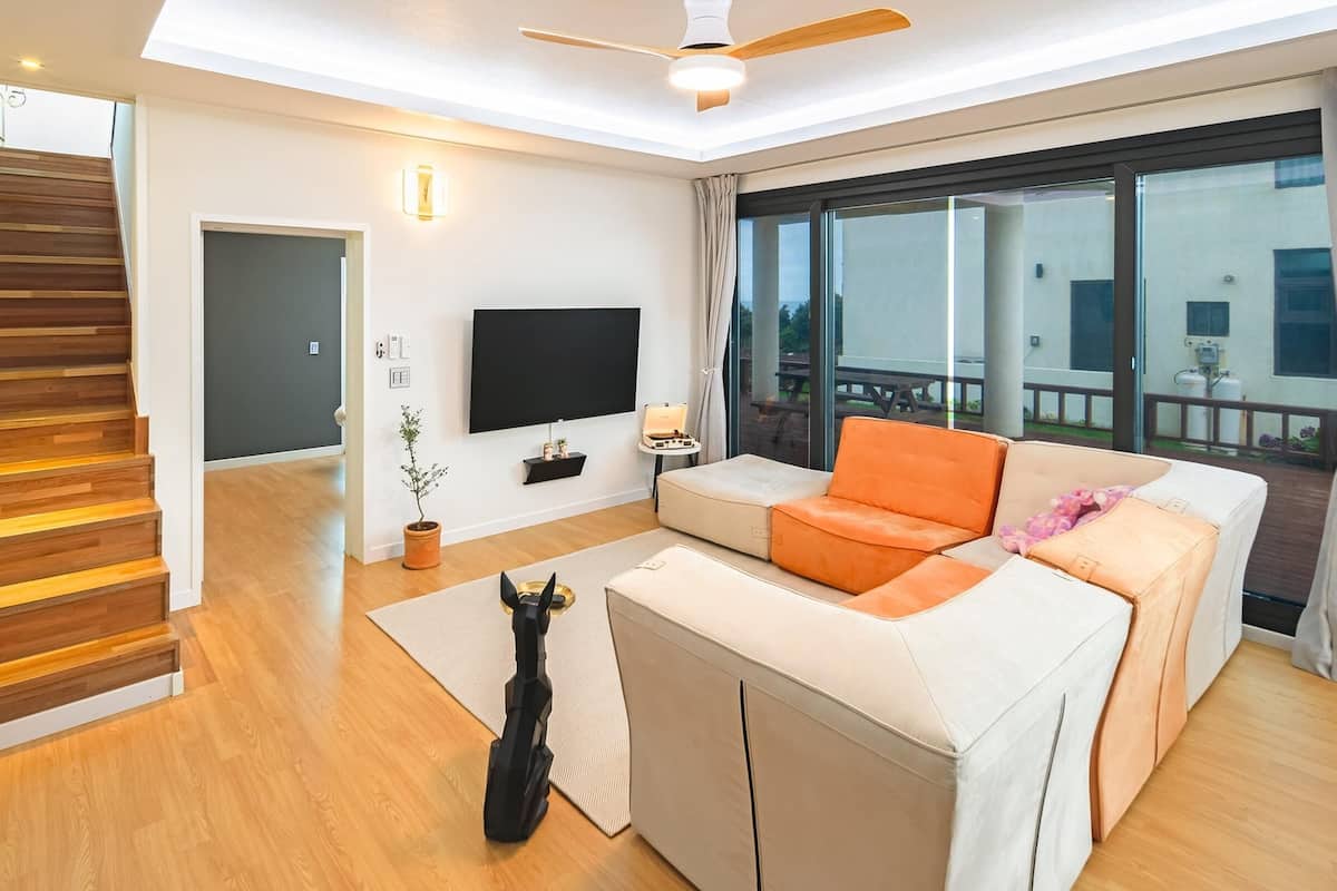 Ein modernes Wohnzimmer mit einer Couch, einem Fernseher und einer Treppe.