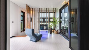 Et moderne interiør med en blå sofa, en spillekonsol og et stort vindue.
