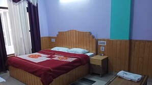 Una habitación con una cama de madera, una mesita de noche, una pequeña mesa y una ventana con cortinas.